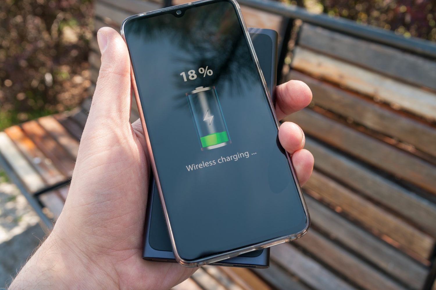 A man charges his phone wirelessly from a power bank.